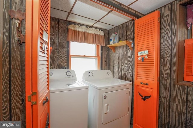 clothes washing area with washer and dryer and wood walls