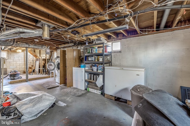 basement with washing machine and clothes dryer and white fridge