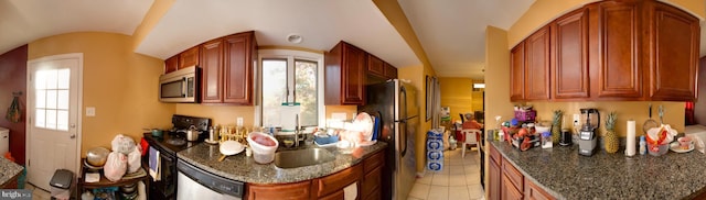 kitchen with light tile patterned flooring, stainless steel appliances, sink, and dark stone countertops