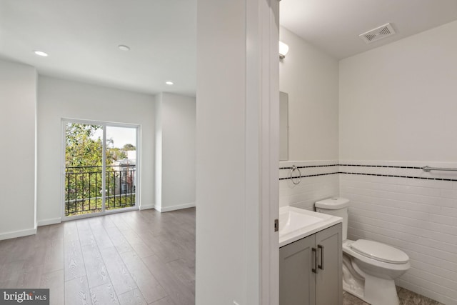 bathroom with toilet, vanity, tile walls, and hardwood / wood-style flooring