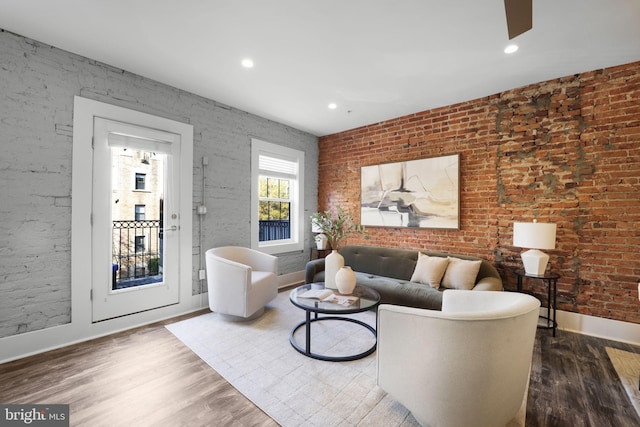 living room featuring wood-type flooring and brick wall