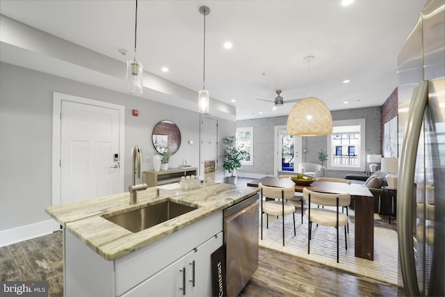 kitchen featuring ceiling fan, sink, white cabinetry, hanging light fixtures, and an island with sink