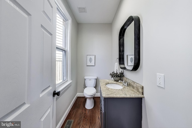 bathroom with hardwood / wood-style floors, vanity, toilet, and a wealth of natural light