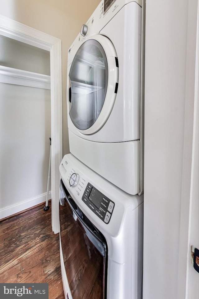 laundry area with dark wood-type flooring and stacked washer / drying machine