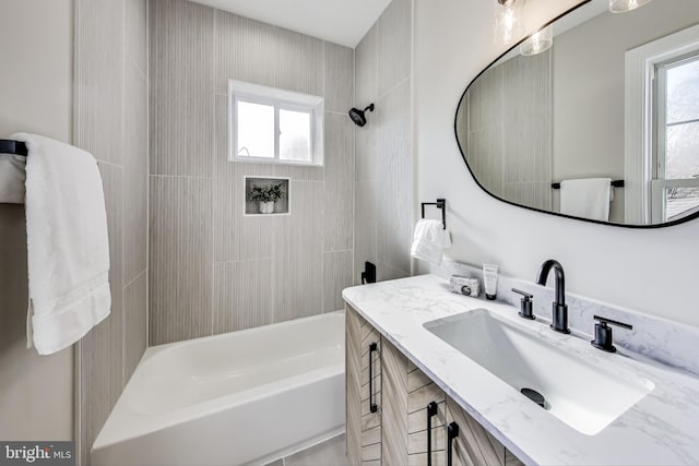 bathroom with vanity, tiled shower / bath combo, and a healthy amount of sunlight