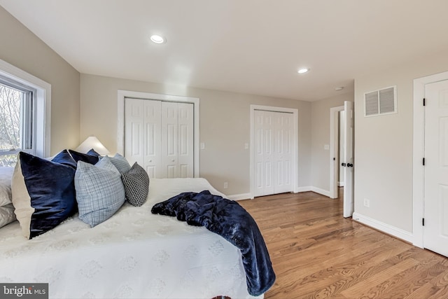 bedroom with wood-type flooring and multiple closets