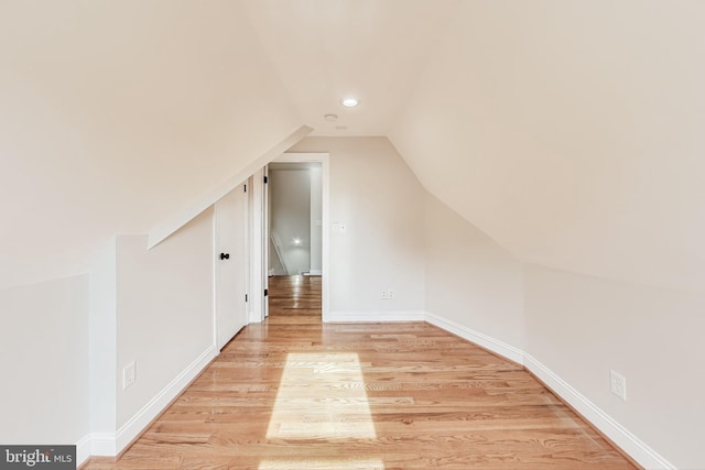 additional living space with light hardwood / wood-style flooring and lofted ceiling