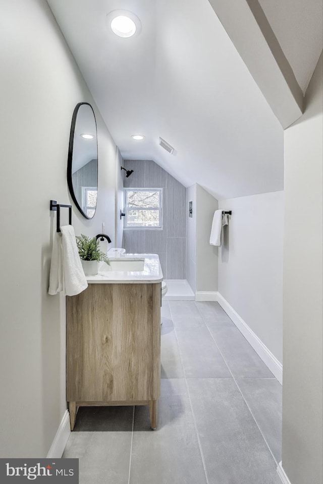 bathroom with vanity, toilet, lofted ceiling, and walk in shower