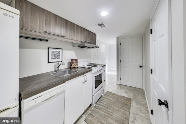 kitchen with white cabinetry, sink, light tile patterned floors, and white appliances