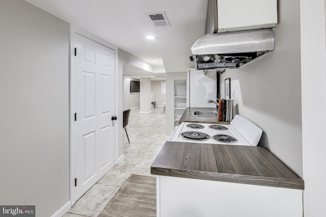 kitchen featuring range hood, light tile patterned flooring, white appliances, and sink