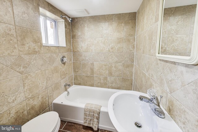 full bathroom featuring sink, tile patterned flooring, toilet, tile walls, and tiled shower / bath