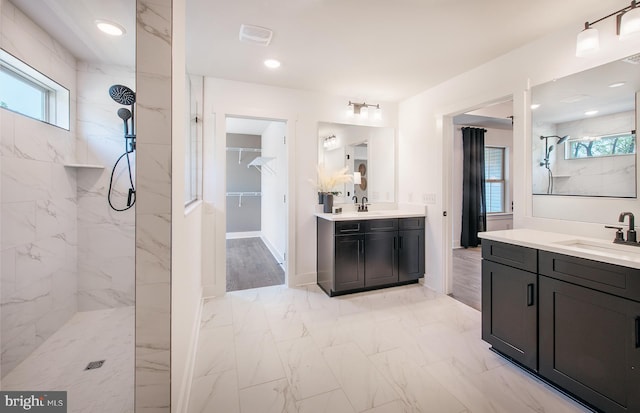 bathroom with a tile shower, vanity, and wood-type flooring