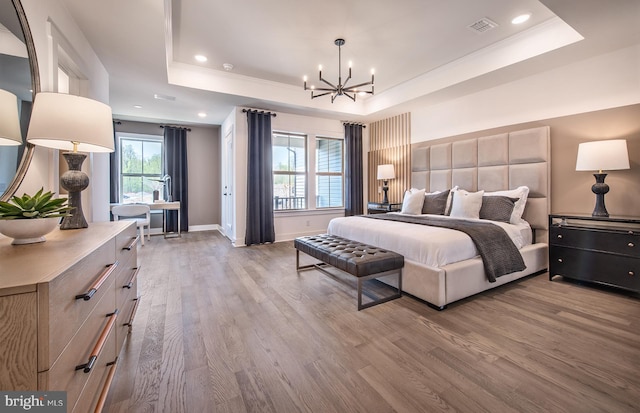 bedroom featuring a tray ceiling, hardwood / wood-style flooring, and a notable chandelier