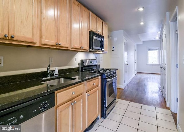 kitchen featuring light hardwood / wood-style floors, sink, stainless steel appliances, and dark stone counters