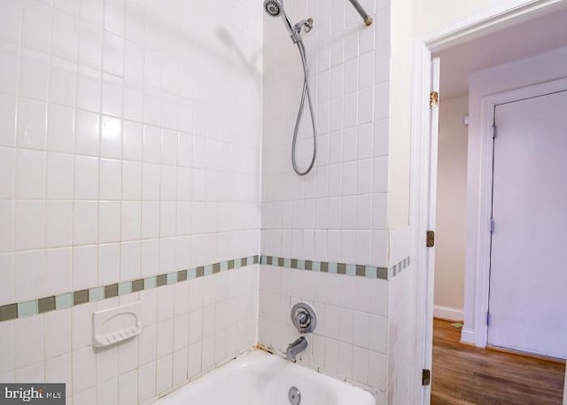 bathroom featuring wood-type flooring and tiled shower / bath