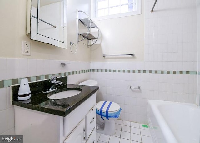 bathroom featuring tile patterned floors, a washtub, vanity, tile walls, and toilet