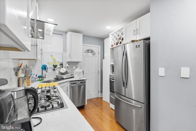 kitchen featuring sink, white cabinets, stainless steel appliances, and light hardwood / wood-style floors