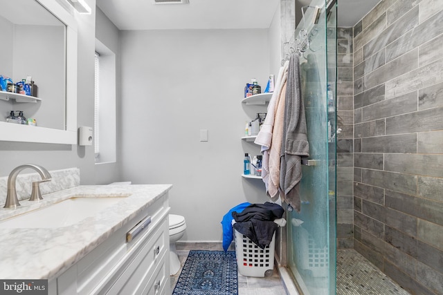 bathroom with tile patterned floors, vanity, toilet, and a shower with door