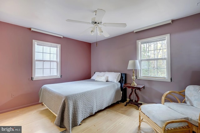 bedroom featuring ceiling fan, light hardwood / wood-style flooring, and multiple windows