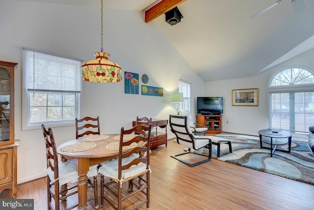 dining area featuring beamed ceiling, high vaulted ceiling, and light hardwood / wood-style flooring