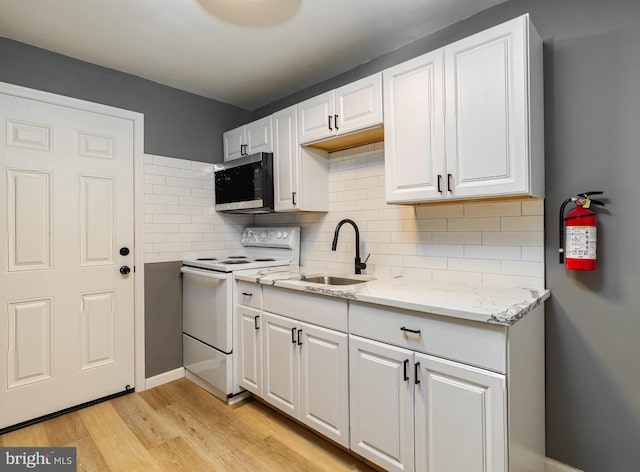 kitchen featuring electric range, tasteful backsplash, white cabinetry, and light hardwood / wood-style flooring