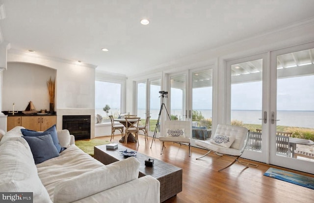 interior space featuring hardwood / wood-style floors, a water view, french doors, and ornamental molding