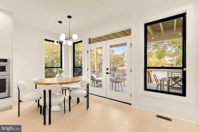 dining room featuring french doors, light hardwood / wood-style flooring, and a notable chandelier