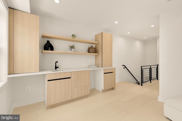 bar with light brown cabinets and sink