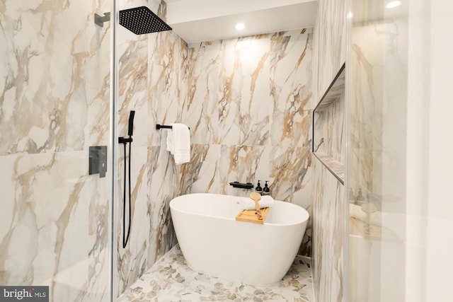 bathroom featuring tile walls and independent shower and bath