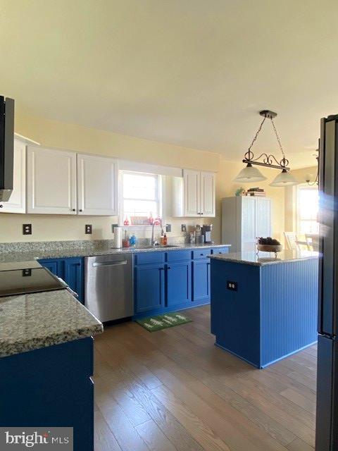 kitchen featuring white cabinetry, appliances with stainless steel finishes, a kitchen island, and hanging light fixtures