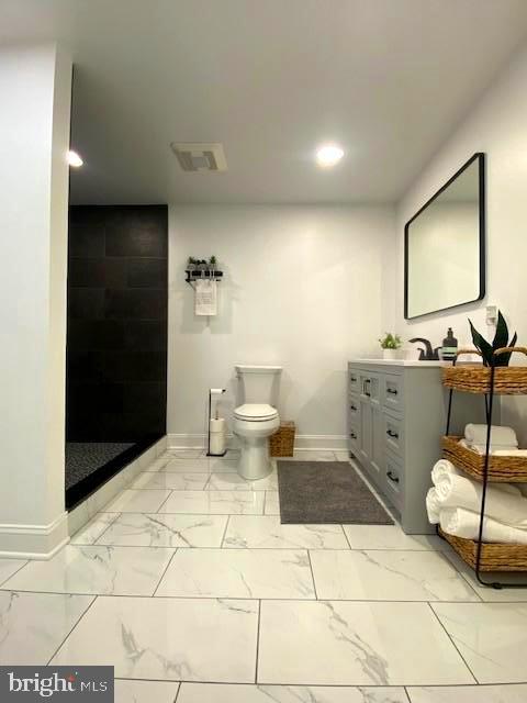 bathroom featuring vanity, toilet, and a tile shower