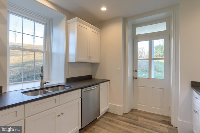 kitchen featuring stainless steel dishwasher, white cabinetry, sink, and a wealth of natural light