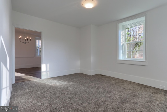 carpeted spare room with a chandelier