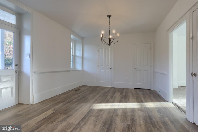 unfurnished dining area with hardwood / wood-style flooring and an inviting chandelier