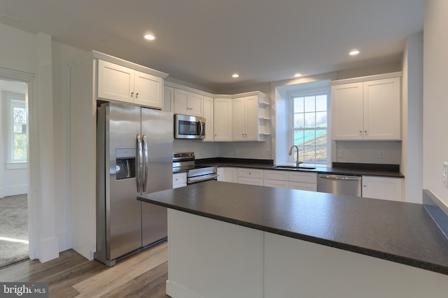 kitchen with plenty of natural light, white cabinets, stainless steel appliances, and light hardwood / wood-style flooring