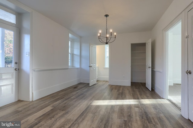 unfurnished dining area featuring hardwood / wood-style flooring and a notable chandelier