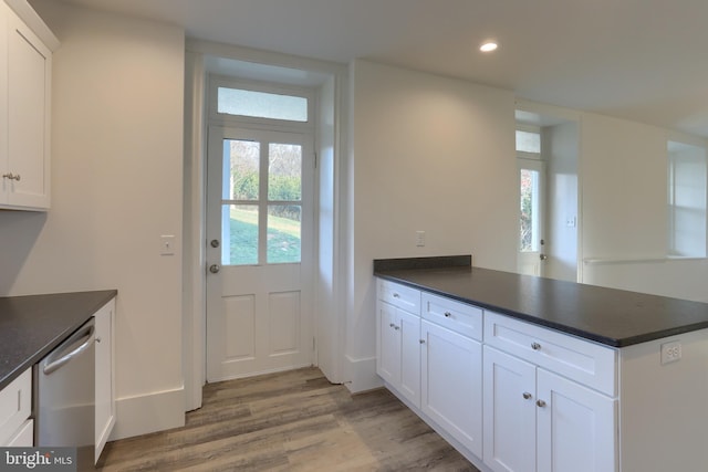 kitchen with white cabinets, light hardwood / wood-style floors, kitchen peninsula, and stainless steel dishwasher