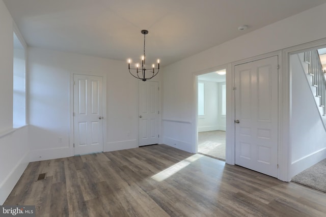 unfurnished dining area with hardwood / wood-style flooring and a notable chandelier