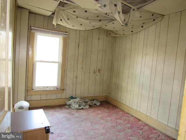 carpeted empty room with wood walls