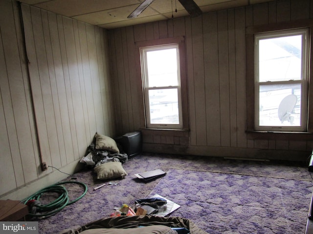 carpeted empty room featuring ceiling fan and wooden walls