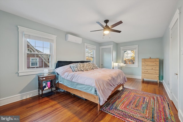 bedroom with a wall unit AC, ceiling fan, and hardwood / wood-style floors