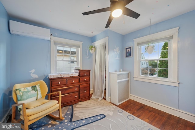 sitting room featuring a wall mounted air conditioner, hardwood / wood-style floors, and ceiling fan