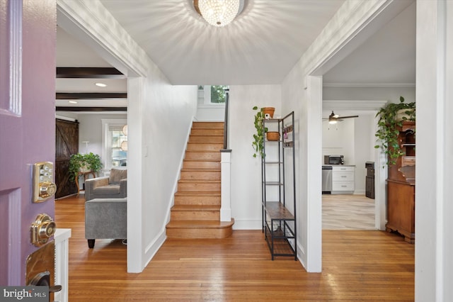 stairway featuring ceiling fan with notable chandelier, a barn door, hardwood / wood-style flooring, and ornamental molding