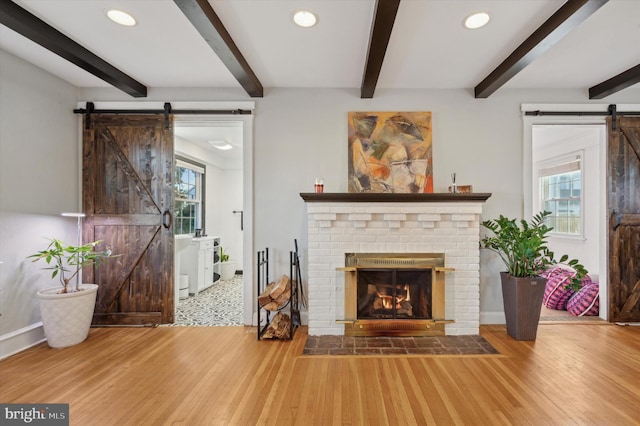 unfurnished living room featuring wood-type flooring, a barn door, and a wealth of natural light