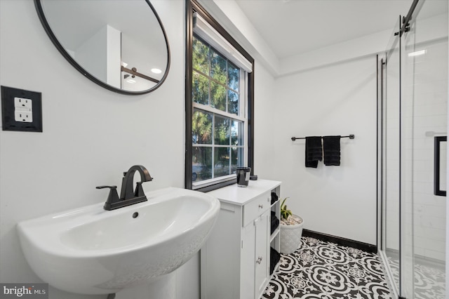 bathroom with sink, a shower with door, and tile patterned flooring