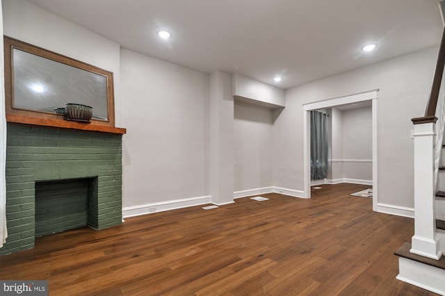 basement with dark hardwood / wood-style floors and a brick fireplace