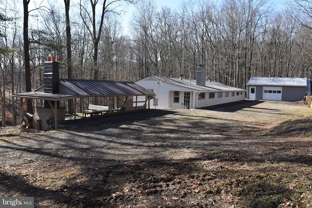 rear view of property featuring a garage and an outbuilding