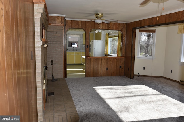 interior space with ceiling fan, wooden walls, and ornamental molding