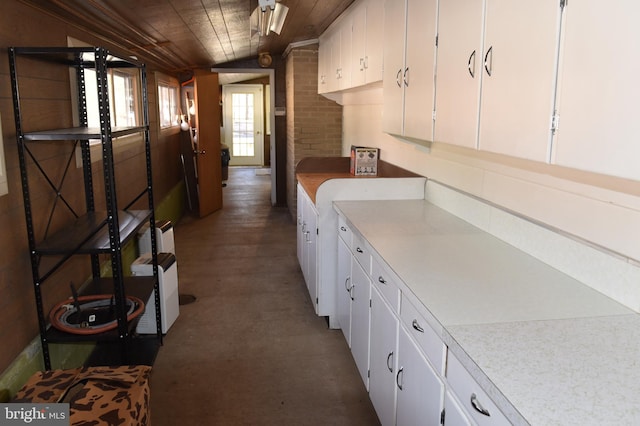 kitchen featuring white cabinetry, wood ceiling, and wooden walls