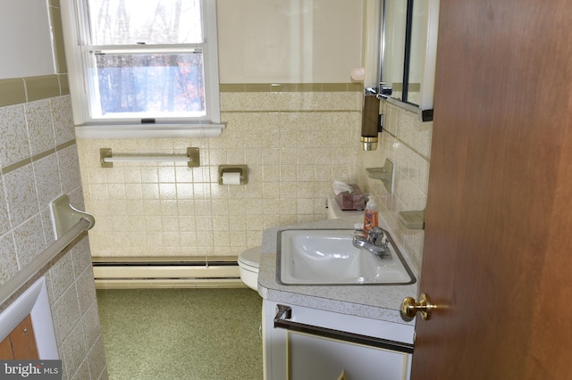 bathroom with toilet, vanity, tile walls, and a baseboard heating unit